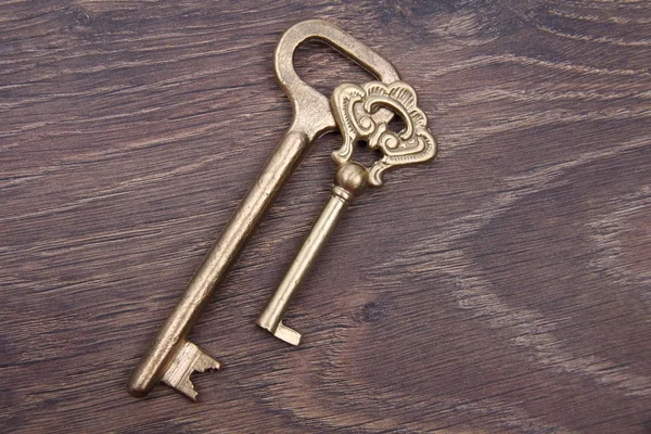 Two ancient keys with ornament on dark wooden background — Stock Photo, Image