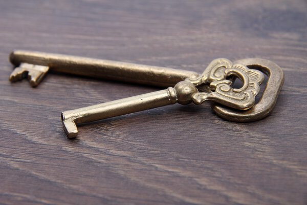 Two ancient keys with ornament on dark wooden background