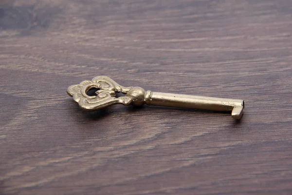Старый ключ с орнаментом на темном деревянном фоне — стоковое фото
