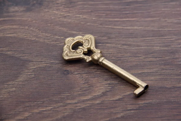 Alter Schlüssel mit Ornament isoliert auf dunklem Holzhintergrund — Stockfoto