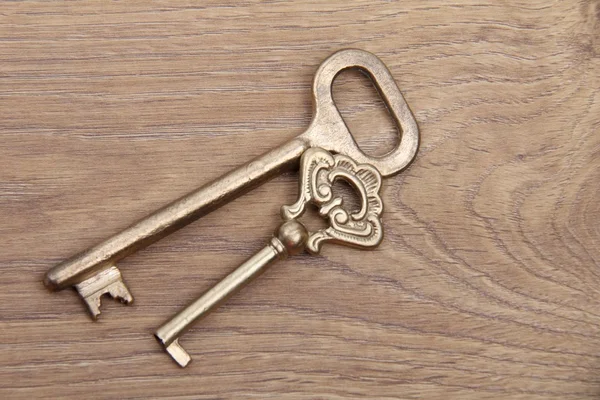 Two ancient keys with ornament on wooden background — Stock Photo, Image