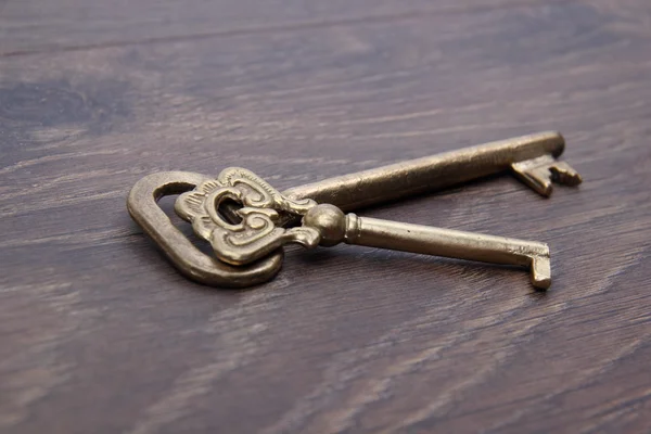 Two vintage keys with ornament on dark wooden background — Stock Photo, Image