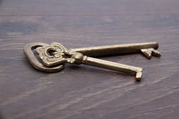 Due chiavi vintage con ornamento su sfondo in legno scuro — Foto Stock