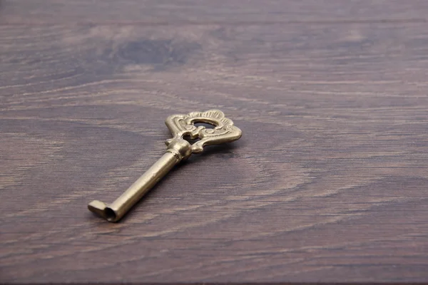 Ancient key with ornament isolated on dark wooden background