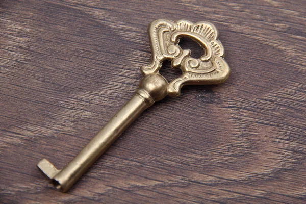 Антикварный ключ с орнаментом на темном деревянном фоне — стоковое фото