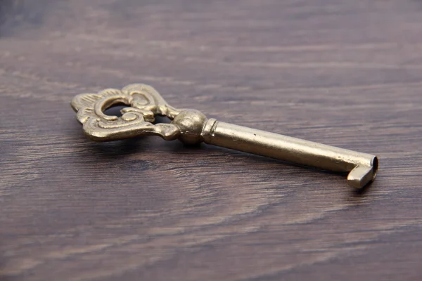 Antik nøgle med ornament på mørk træ baggrund - Stock-foto