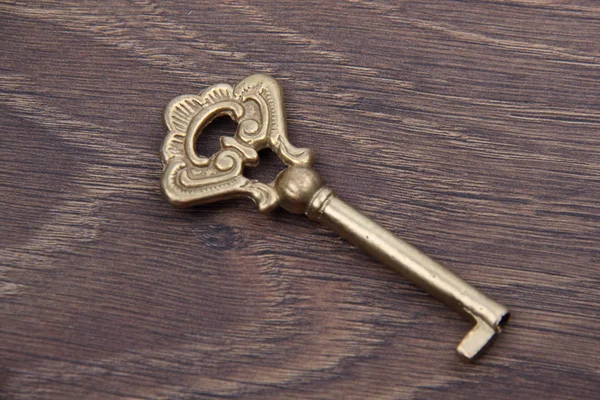 Starožitný klíč s ornament na tmavé dřevěné pozadí — Stock fotografie