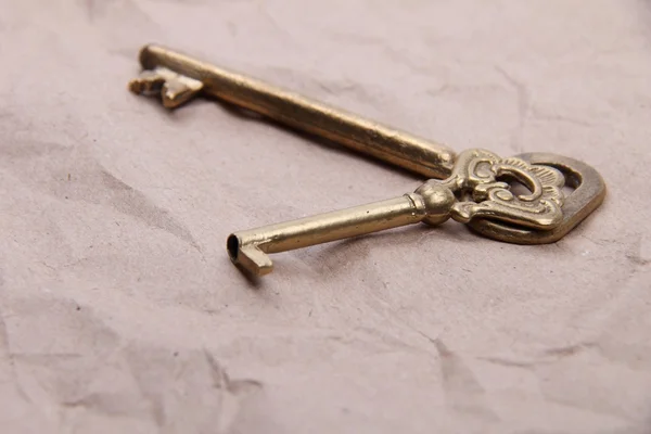 Two antique keys with ornament on a background of crumpled paper — Stock Photo, Image