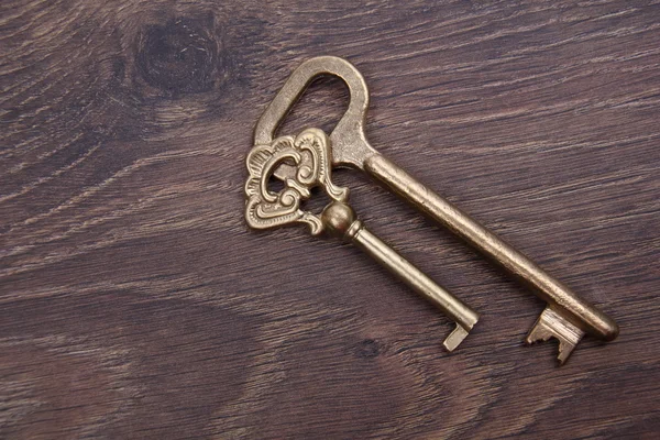 Dva staré klíče s ornament na dřevěné pozadí — Stock fotografie