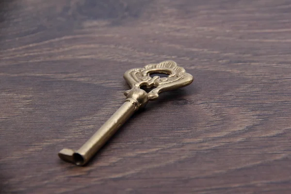Vieille clé avec ornement sur fond bois foncé — Photo