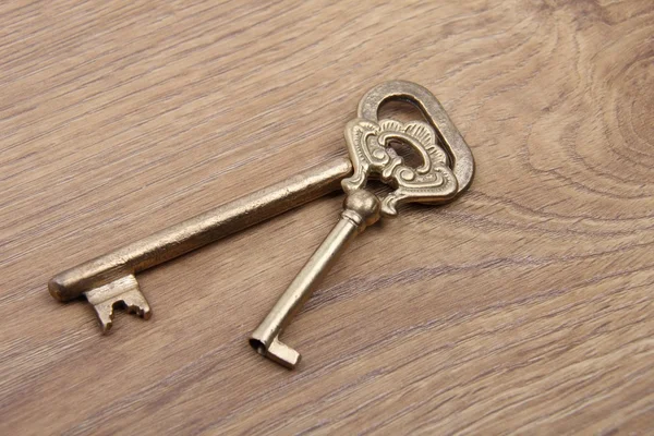 Two old keys with ornament on wooden background — Stock Photo, Image