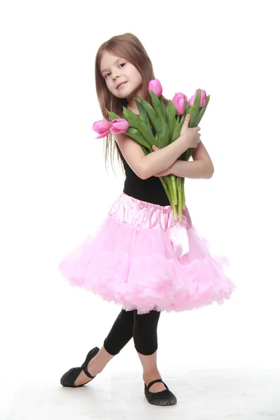 Beautiful little ballerina in a tutu holding a big bouquet of tulips — Stock Photo, Image