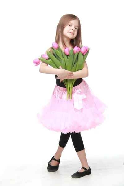 Beautiful little ballerina in a tutu holding a big bouquet of tulips — Stock Photo, Image