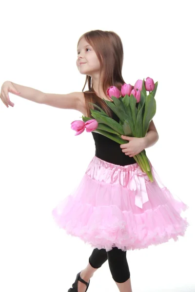 Petite fille mignonne dans un tutu avec des tulipes sur un fond blanc — Photo