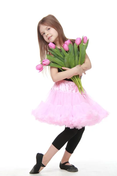 Charming little dancer with long hair holding a beautiful bouquet of tulips — Stock Photo, Image
