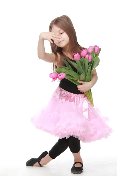 Emotional little ballerina in a tutu holding a big bouquet of tulips — Stock Photo, Image