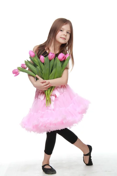 Hezká malá tanečnice s dlouhými vlasy drží krásné kytice tulipánů — Stock fotografie