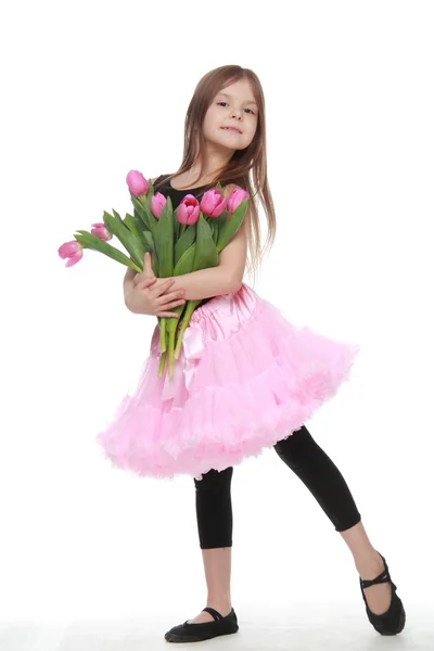 Llittle ballerina in a tutu holding a big bouquet of tulips — Stock Photo, Image