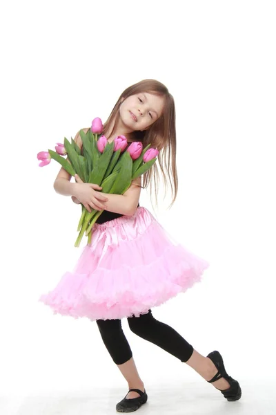 Beautiful little ballerina in a tutu holding a big bouquet of tulips — Stock Photo, Image