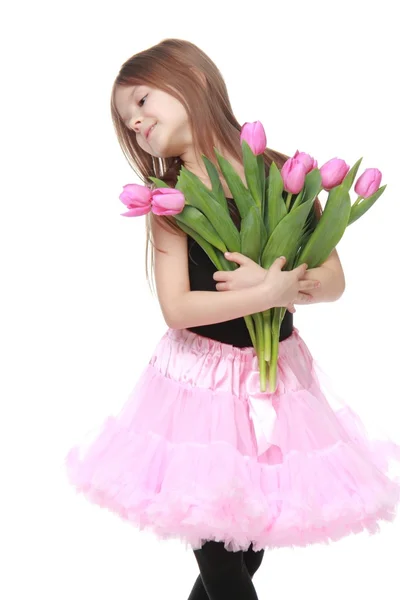 Vackra lilla ballerina i en tutu innehar en stor bukett tulpaner — Stockfoto