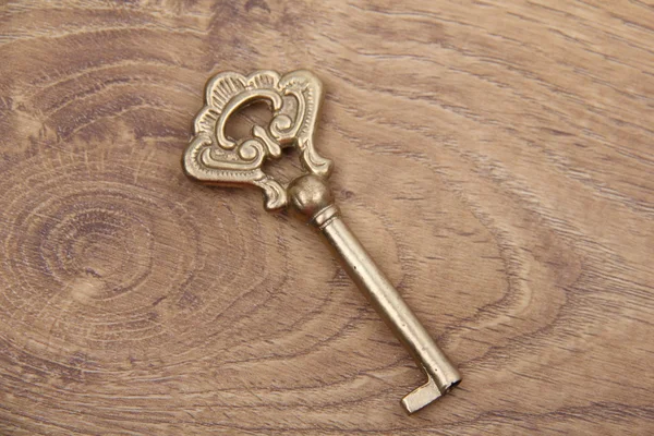 Ancient key with ornament isolated on wooden background — Stock Photo, Image