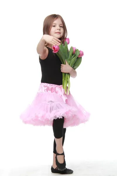 Ballerina in een tutu met een boeket van tulpen is in een ballet pose — Stockfoto