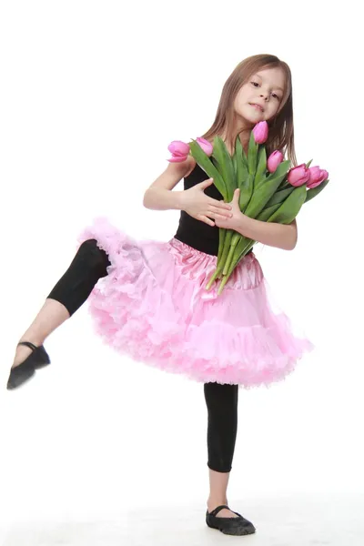 Niedliche kleine Tänzerin mit langen Haaren hält einen schönen Strauß Tulpen — Stockfoto