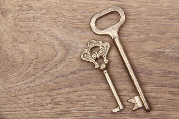 Two ancient keys with ornament on wooden background — Stock Photo, Image