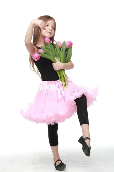Emotional little ballerina in a tutu holding a big bouquet of tulips — Stock Photo, Image