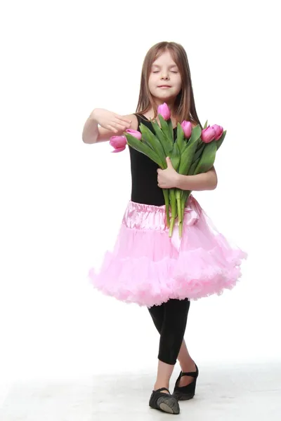 Emotional little ballerina in a tutu holding a big bouquet of tulips — Stock Photo, Image