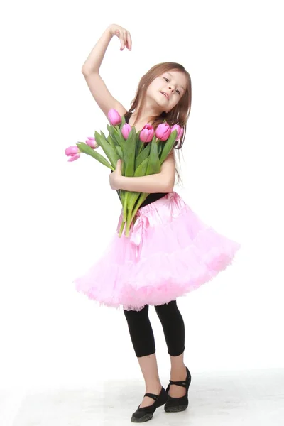 Mooie kleine danser met lange haren die een mooi boeket van tulpen — Stockfoto