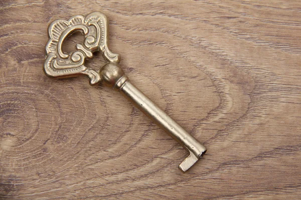 Old key with ornament on wooden background — Stock Photo, Image