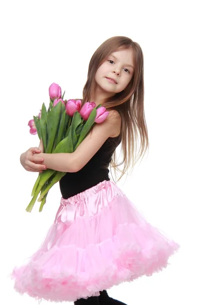 Маленькая танцовщица с длинными волосами держит красивый букет тюльпанов — стоковое фото