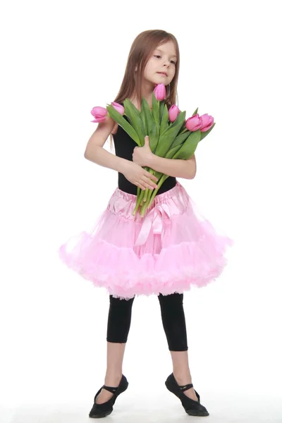 Ballerina in a tutu with a bouquet of tulips is in a ballet pose — Stock Photo, Image