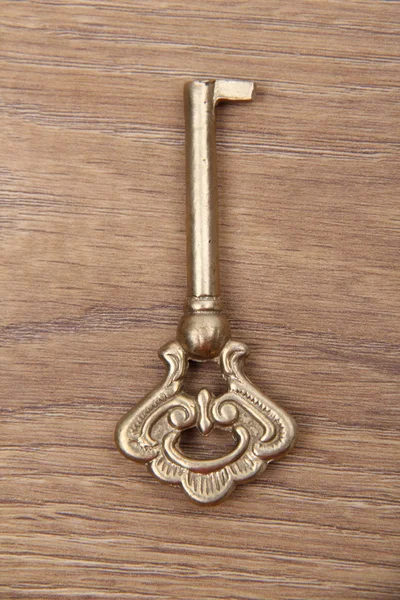 Starý klíč s ornament na dřevěné pozadí — Stock fotografie