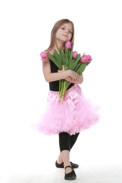 Hezká malá tanečnice s dlouhými vlasy drží kytici tulipánů — Stock fotografie