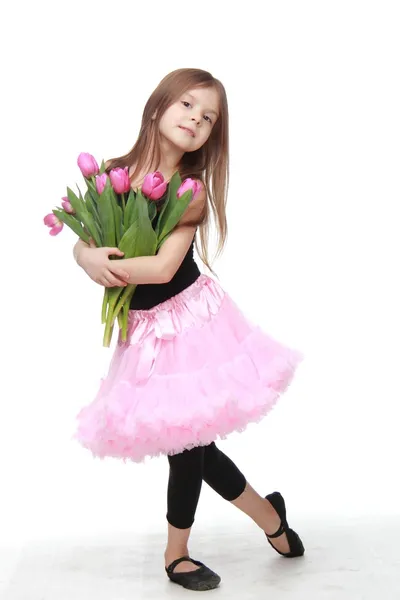 Маленькая танцовщица с длинными волосами держит большой букет тюльпанов — стоковое фото