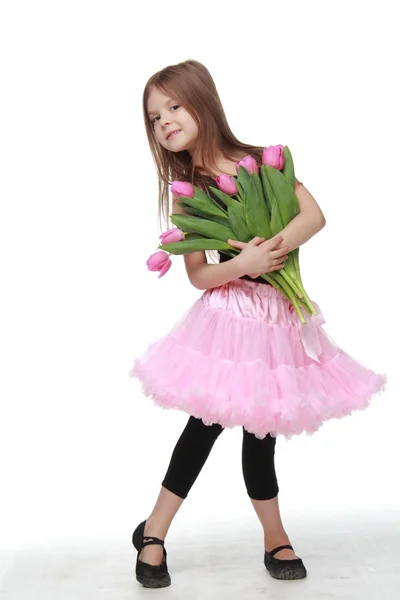 Llittle ballerina in a pink tutu holding a big bouquet of tulips — Stock Photo, Image