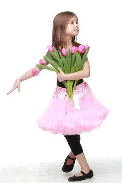 Милая маленькая танцовщица с длинными светлыми волосами, держащая большой букет тюльпанов — стоковое фото