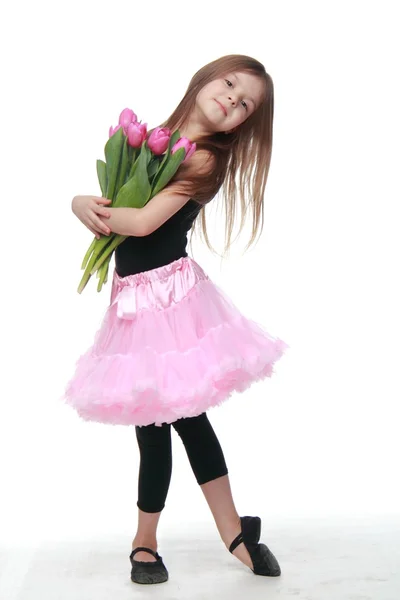 Cute little dancer with long blond hair holding a bouquet of tulips — Stock Photo, Image