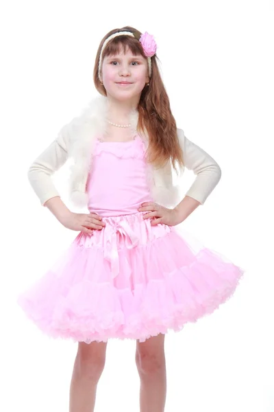 Krásné dítě s nádhernými vlasy v růžové sukénce pózuje pro fotoaparát — Stock fotografie