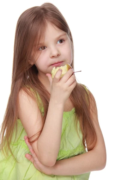 小さな女の子が魅力的な緑のシャツの食用リンゴ — ストック写真