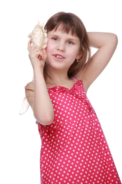 Little girl in summer clothes holding a large sea shell on the sea and the summer — Stock Photo, Image