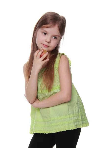 Encantadora niña con camisa verde comiendo una manzana — Foto de Stock