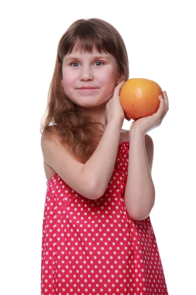 Маленькая девочка в ярком платье держит грейпфрут — стоковое фото
