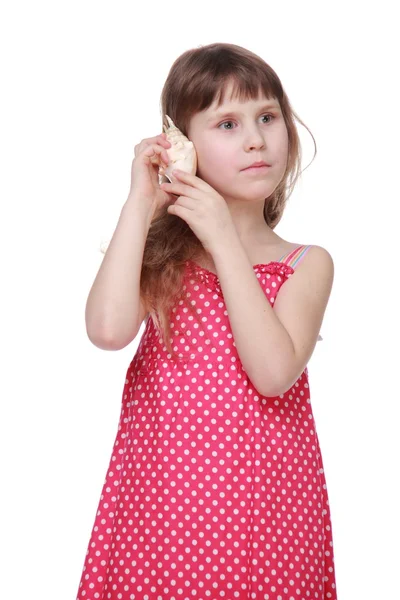 Niedliches kleines Mädchen in einem hellen Kleid mit einer Muschel — Stockfoto