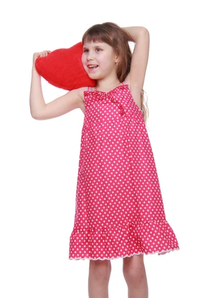 Cheerful little girl in a dress holding a toy heart — Stock Photo, Image