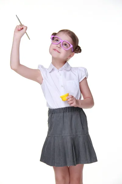 Студийное изображение школьницы с очками, позирующей с краской и кистью — стоковое фото
