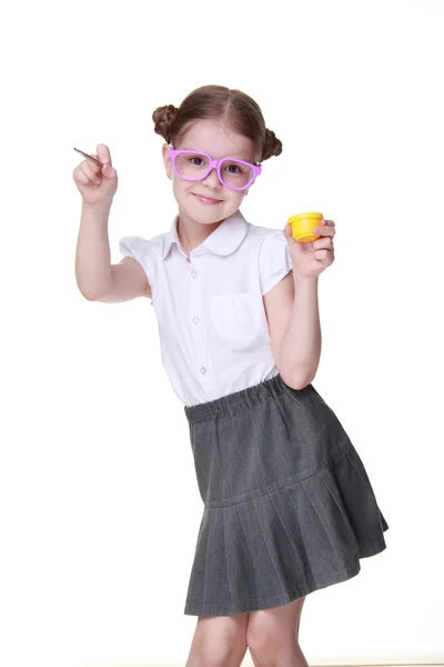 Atelierbild von Schulmädchen mit lustiger Brille posiert mit gelber Farbe und Pinsel — Stockfoto