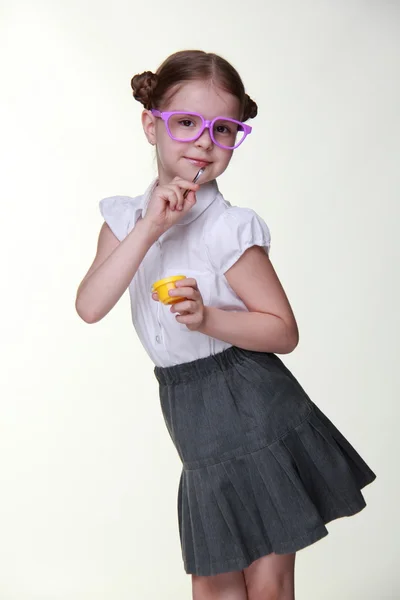 Studio bilden av skolflicka med roliga glasögon poserar med gul färg och pensel — Stockfoto